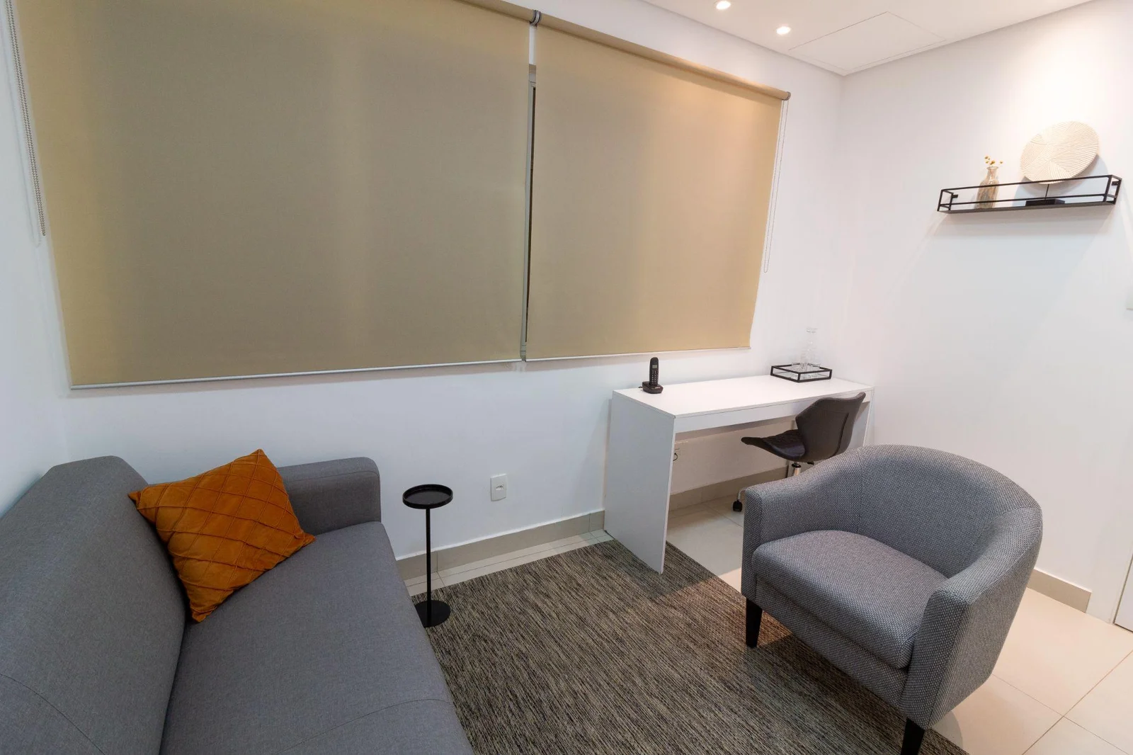 Consultório de psicologia na Vila Mariana com sofá cinza e iluminação acolhedora