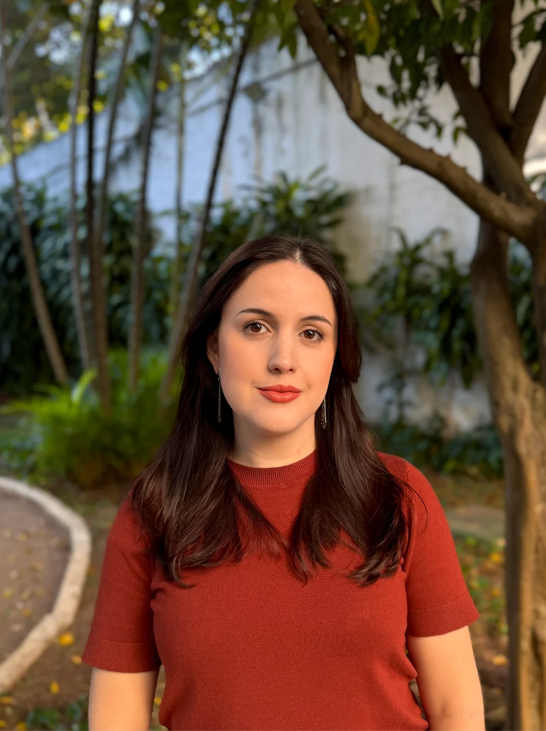 Nicole Vegi Capuzzo, psicóloga, retrato profissional em ambiente com vegetação